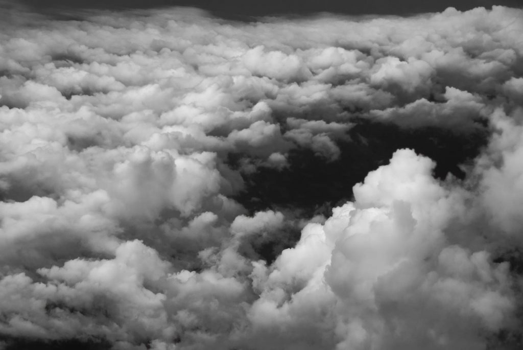 Black and White image showing the parting of the clouds to give a glimpse of what lies beneath